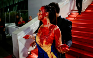 O femeie îmbrăcată în culorile drapelului Ucrainei și-a turnat pungi cu sânge fals pe corp, pe covorul roşu de la Cannes